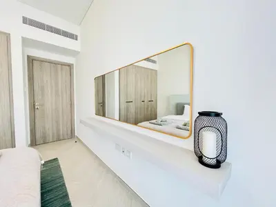 a white bedroom with a large mirror on a wall at Brand New Luxury 1 Bedroom Apartment in Dubai