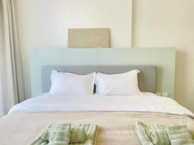 a bed with white pillows and two towels on it at Brand New Luxury 1 Bedroom Apartment in Dubai
