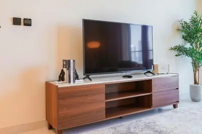 a flat screen tv sitting on top of a wooden entertainment center at Beachfront Bliss - Apartment with Pool and Premium Amenities By ĀYA Boutique in Dubai