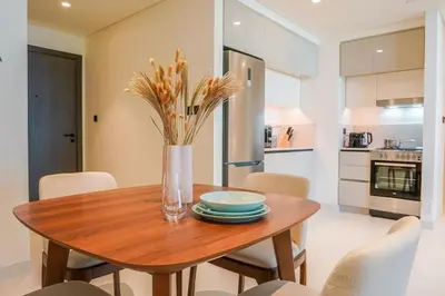 a wooden table with plates and a vase with flowers at Beachfront Bliss - Apartment with Pool and Premium Amenities By ĀYA Boutique in Dubai