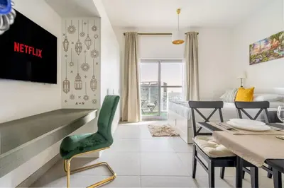 a living room with a table and a green chair at GuestReady - Bella Rose residence in Dubai in Dubai