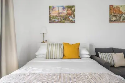 a white bed with yellow pillows and a couch at GuestReady - Bella Rose residence in Dubai in Dubai