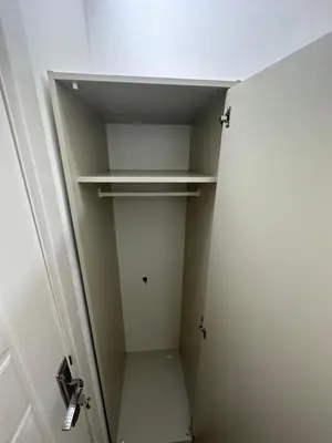 a small closet with white shelves and a door at Lovely Private Partition Room in Barsha Heights in Dubai