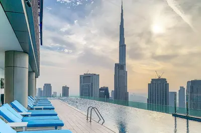 a pool with chaise lounge chairs on the roof of a building with a view at Frank Porter - Paramount in Dubai
