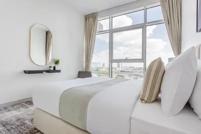 a white bedroom with a large bed and a large window at Frank Porter - Park Gate Residences 1 in Dubai