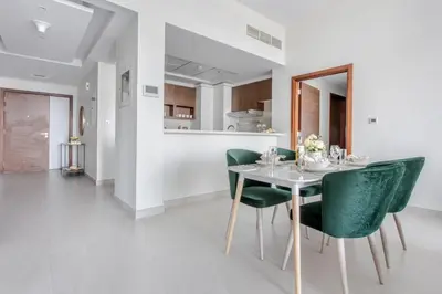 a dining room with a table and green chairs at Frank Porter - Park Gate Residences 1 in Dubai