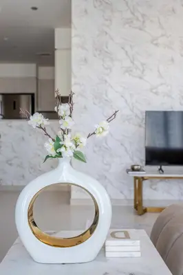 a white vase with flowers in it on a table at Frank Porter - Burj Royale in Dubai