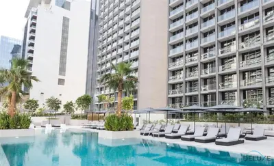 a pool with chairs and umbrellas in front of a building at Burj Khalifa Views! Promo on 1BR at Sterling House by Deluxe Holiday Homes in Dubai