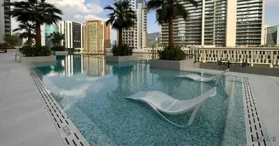 a swimming pool with two white chairs on a building at Burj Khalifa Views! Promo on 1BR at Sterling House by Deluxe Holiday Homes in Dubai