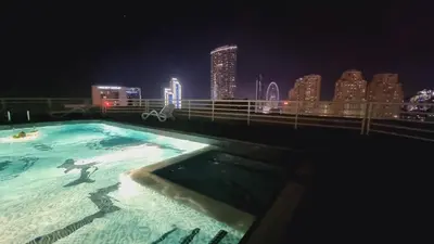 a swimming pool with a city skyline at night at Marina View Manchester tower in Dubai