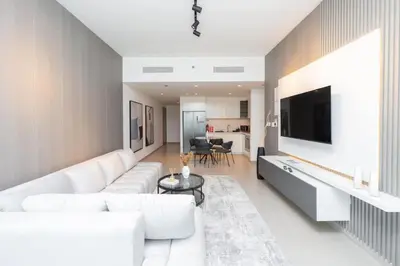 a living room with a white couch and a tv at The Legend Fashionable 2 Bed Apartment in Downtown in Dubai