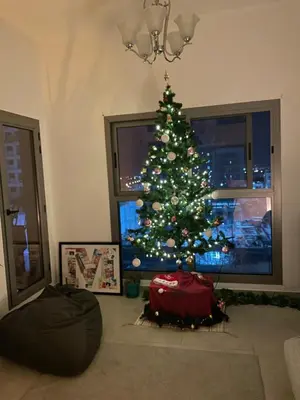a living room with a christmas tree in front of a window at Burj Khalifa view/ Cozy apartment in Dubai