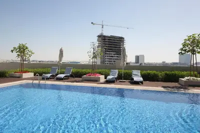 a swimming pool with lounge chairs and a building at Aura Azizi - Downtown Jabel Ali by Golden Casa in Dubai