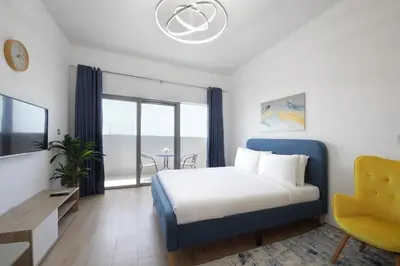 a bedroom with a bed and a yellow chair at Aura Azizi - Downtown Jabel Ali by Golden Casa in Dubai