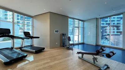 a gym with cardio equipment in a large room with windows at Keyrock Living - Studio with Burj Khalifa View in Dubai