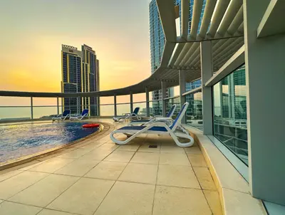 a balcony with a pool and chairs on a building at Unforgettable Canal & Sea View in Dubai Marina in Dubai