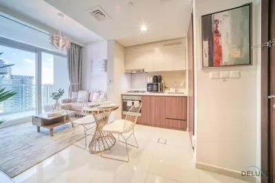 a kitchen and living room with a table and chairs at Hot Offer Modern 1BR with Scenic Water Canal Views by Deluxe Holiday Homes in Dubai