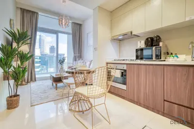 a kitchen and dining room with a table and chairs at Hot Offer Modern 1BR with Scenic Water Canal Views by Deluxe Holiday Homes in Dubai