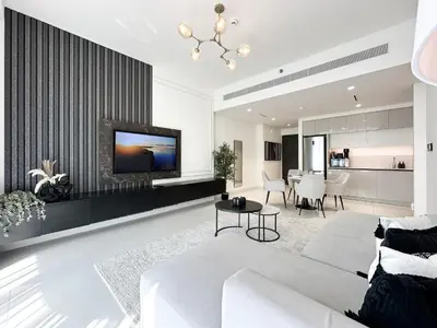 a living room with a white couch and a tv at Trophy - Marina Vista Sea View Suite in Dubai
