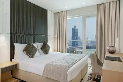 a hotel room with a bed and a desk and a window at DAMAC Maison Canal Views in Dubai