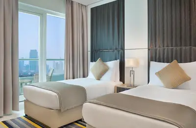 a hotel room with two beds and a large window at DAMAC Maison Canal Views in Dubai