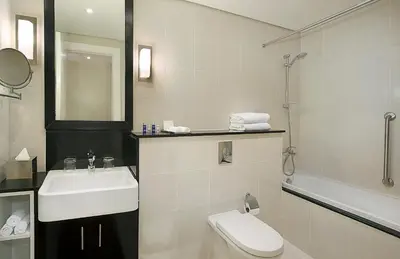 a white bathroom with a sink and a toilet at DAMAC Maison Canal Views in Dubai