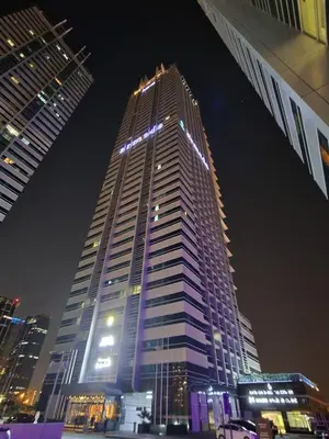 a tall building with lights on top of it at night at Armada Avenue Hotel in Dubai
