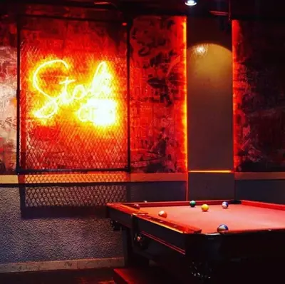 a pool table in a room with a neon sign at Armada Avenue Hotel in Dubai