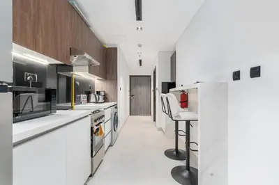 a kitchen with white counters and a bar stool at Unique Studio in JVC - Dubai in Dubai