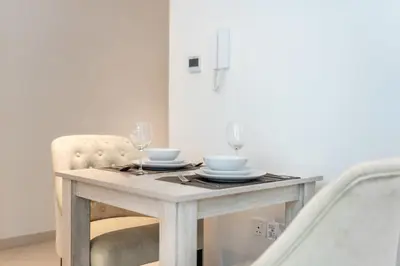 a dining room table with two glasses and a chair at Modern 1BR Seven Palm Private Beach Infinity Pool in Dubai
