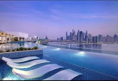 a hotel swimming pool with a view of a city at Modern 1BR Seven Palm Private Beach Infinity Pool in Dubai