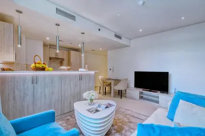 a living room with a blue couch and a kitchen at Modern 1BR Seven Palm Private Beach Infinity Pool in Dubai