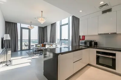 a kitchen with white cabinets and a living room at Spacious I Burj Khalifa View I District One in Dubai