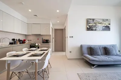 a kitchen and living room with a table and a couch at Downtown Luxurious 1BR Near Dubai Mall and Fountain in Dubai