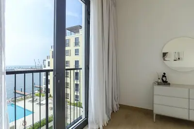 a room with a large window with a view of the ocean at HiGuests - Dream stay in our Cozy 2BR in La Rive Community in Dubai
