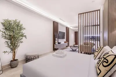 a bedroom with a white bed and a living room at Stylish Studio Walk to Dubai Mall & Burj Khalifa in Dubai