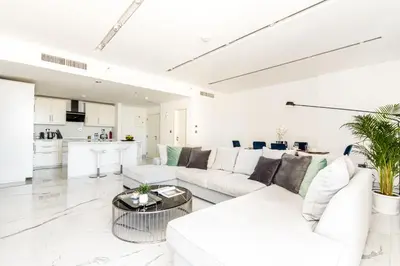a white living room with a white couch and a table at GMA Murjan 2BR Sea View High Floor in Dubai