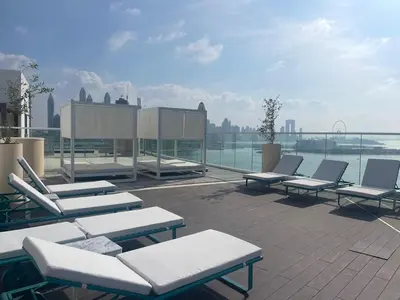 a group of lounge chairs and tables on a roof at Fully-equipped studio Palm Jumeirah, Seven in Dubai