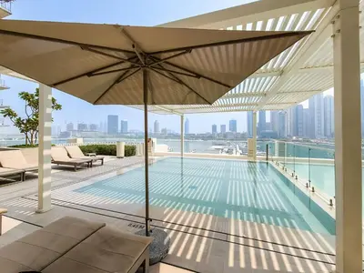 a swimming pool with an umbrella on a building at Marina Vista 1BD with beach access in Beachfront in Dubai