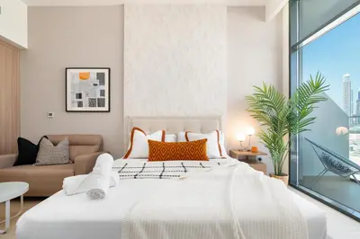 a bedroom with a large white bed and a couch at ON OFF HH-Meydan One- Cozy STUDIO - Burj Khalifa & Lagoon view in Dubai