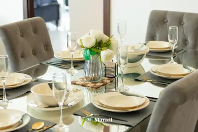 a table with plates and glasses and a vase of flowers at Manzil - 3BR in Boulevard Point connected to Dubai Mall with Incredible View of Burj Khalifa in Dubai