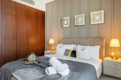 a bedroom with a large bed with two lamps and towels at Manzil - 3BR in Boulevard Point connected to Dubai Mall with Incredible View of Burj Khalifa in Dubai