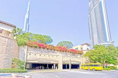a yellow van parked in front of a building with flowers at Golden Homes Souk Al Bahar Burj khalifa view Tajer residences 1BR Mint avenue Near , Dubai mall & burj khalifa in Dubai