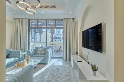a living room with a couch and a tv at Golden Homes Souk Al Bahar Burj khalifa view Tajer residences 1BR Mint avenue Near , Dubai mall & burj khalifa in Dubai