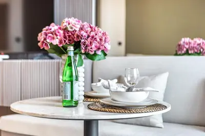 a table with a green bottle and pink flowers on it at The Smart Concierge - Binghatti Canal in Dubai