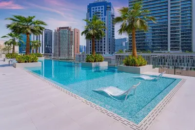 a swimming pool on the roof of a building with palm trees at Voguish studio! Walk to Burj Khalifasleeps 3! in Dubai