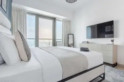 a white bedroom with a large bed and windows at Frank Porter - Ocean Heights in Dubai