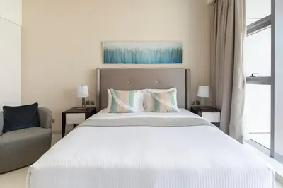 a bedroom with a large white bed and a chair at Frank Porter - Avanti Tower in Dubai