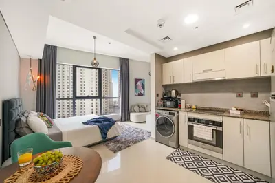 a bedroom with a bed and a kitchen with a table at Iolanda Home in Dubai