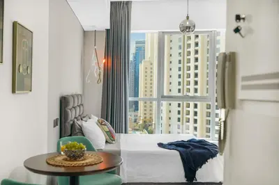a bedroom with a bed and a table and a window at Iolanda Home in Dubai